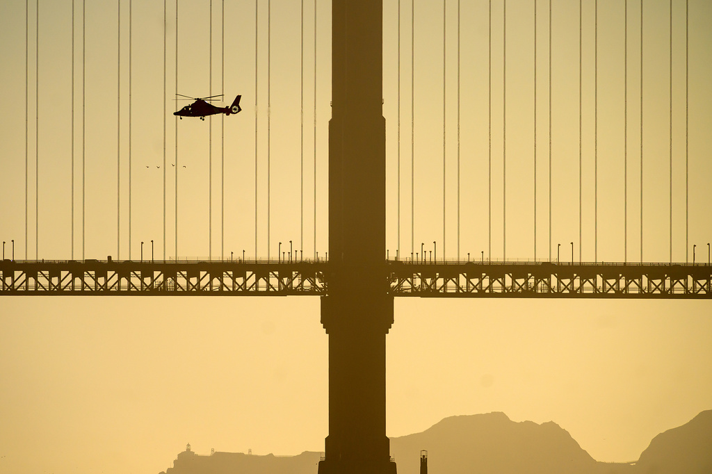 A helicopter flies past the Golden Gate Bridge while searching for missing victims after a boat accident near Alcatraz Island off San Francisco, Tuesday, July 14, 2026. (AP Photo/Noah Berger)