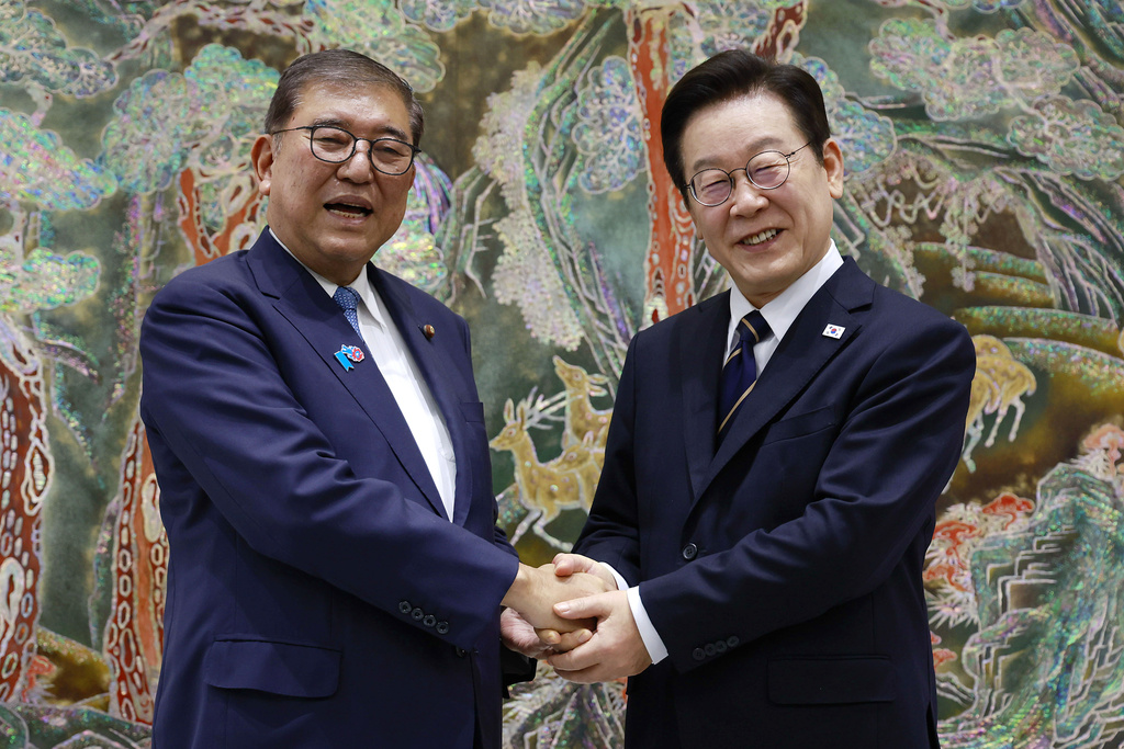 South Korean President Lee Jae Myung, right, shakes hands with Japanese Prime Minister Shigeru Ishiba, left, during a meeting in Busan, South Korea, Tuesday, Sept. 30, 2025. (Yonhap via AP)