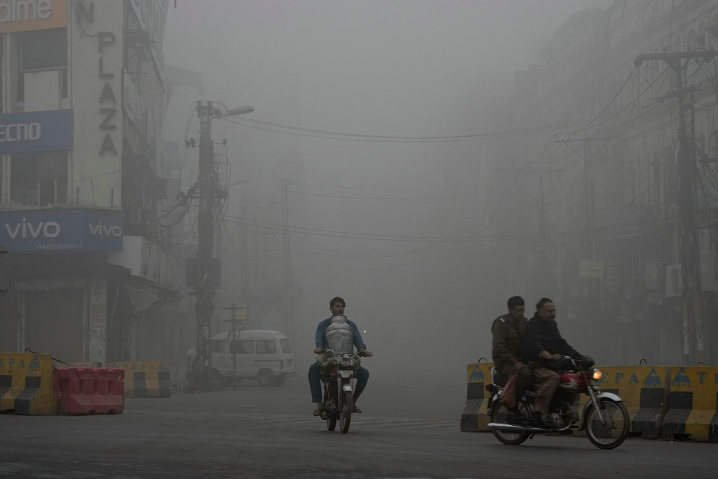 FILE - Motorcyclists drive on a road as smog envelopes the area of Lahore, Pakistan, Nov. 16, 2024. (AP Photo/K.M. Chaudary, File)