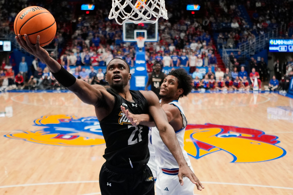 Towson forward Jack Doumbia Jr. (21) shoots under pressure from Kansas forward Samis Calderon during the second half of an NCAA college basketball game Tuesday, Dec. 16, 2025, in Lawrence, Kan. (AP Photo/Charlie Riedel)
