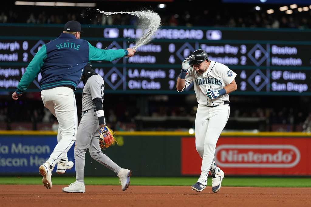 Seattle Mariners' Luke Raley, left, throws water on Cal Raleigh to celebrate Raleigh's game-winning single as New York Yankees second baseman Jazz Chisholm Jr. walks away after a baseball game, Monday, March 30, 2026, in Seattle. (AP Photo/Lindsey Wasson)