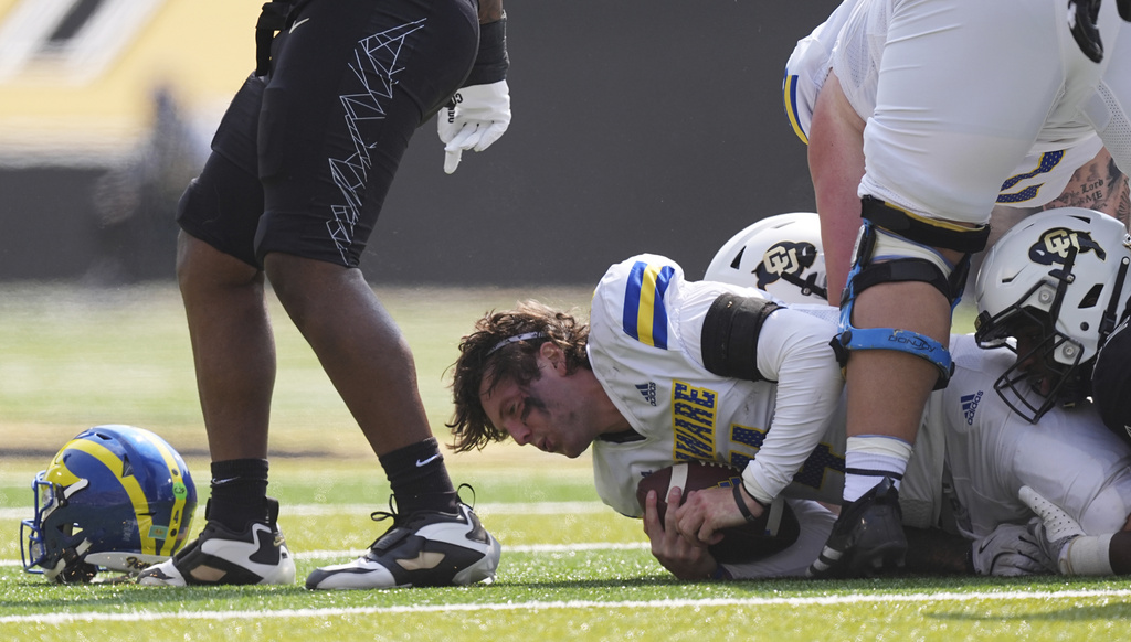 Delaware quarterback Nick Minicucci, left, loses his helmet as he is tackled by Colorado defenders in the first half of an NCAA college football game Saturday, Sept. 6, 2025, in Boulder, Colo. (AP Photo/David Zalubowski)