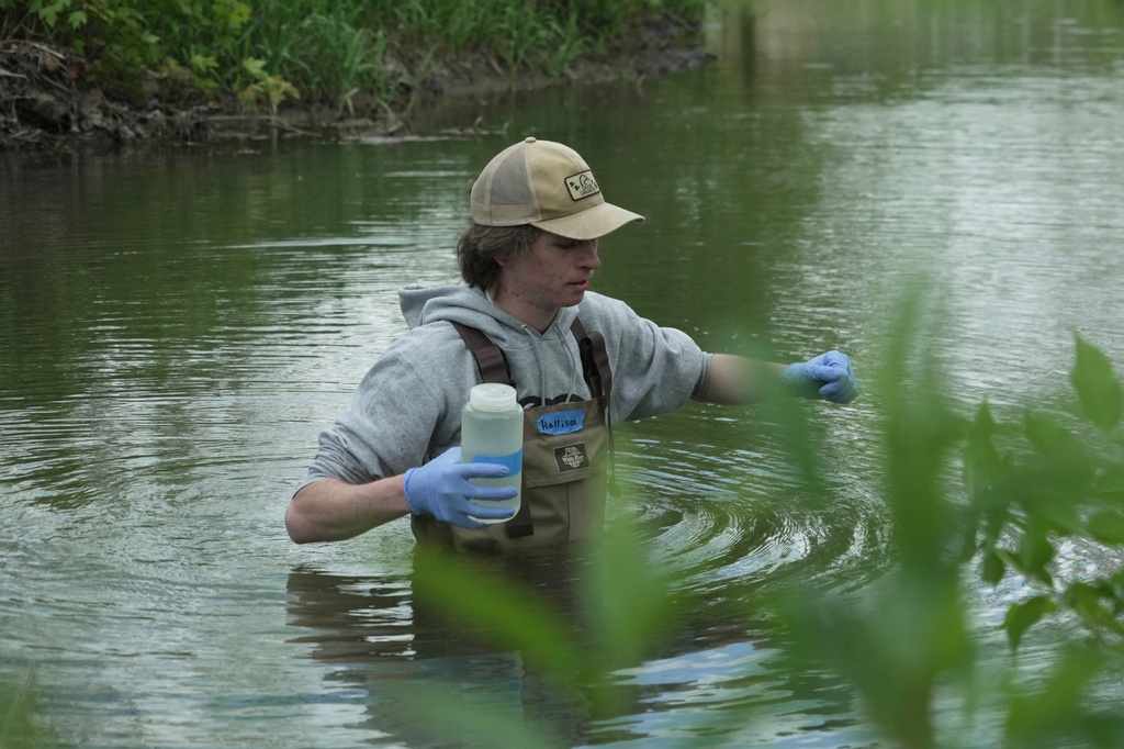 Drake University student Harrison Ziegler holds a bottle as he collects a water sample Wednesday, May 6, 2026, in Des Moines, Iowa. (AP Photo/Brittany Peterson)