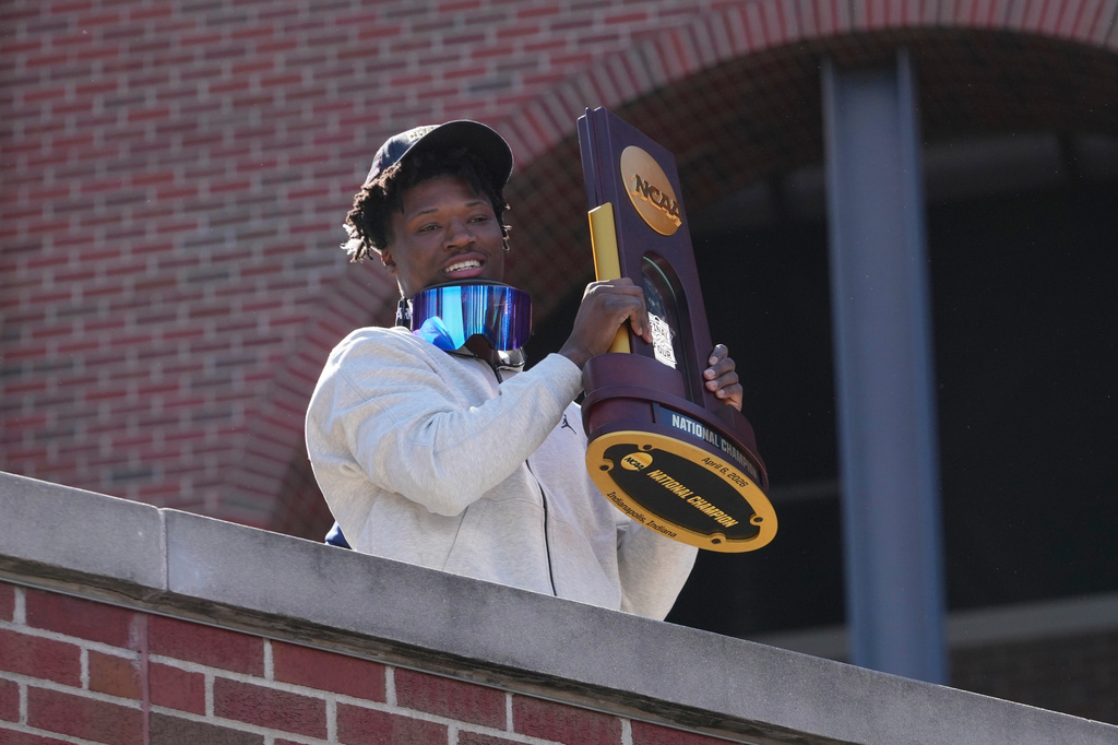 Michigan's L.J. Cason holds the National Championship trophy upon returning to campus Tuesday, April 7, 2026, in Ann Arbor, Mich., the day after defeating UConn at the Final Four of the NCAA college basketball tournament. (AP Photo/Paul Sancya)