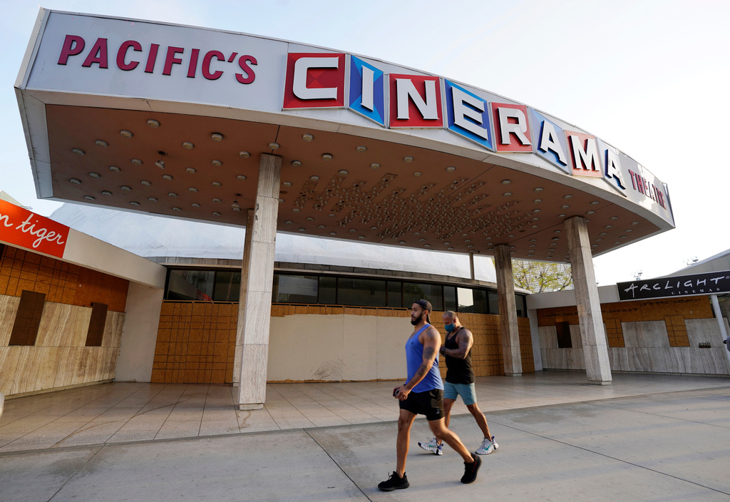 FILE - Pedestrians walk past the boarded up and closed Cinerama Dome movie theater in Los Angeles on April 12, 2021. (AP Photo/Chris Pizzello, File)