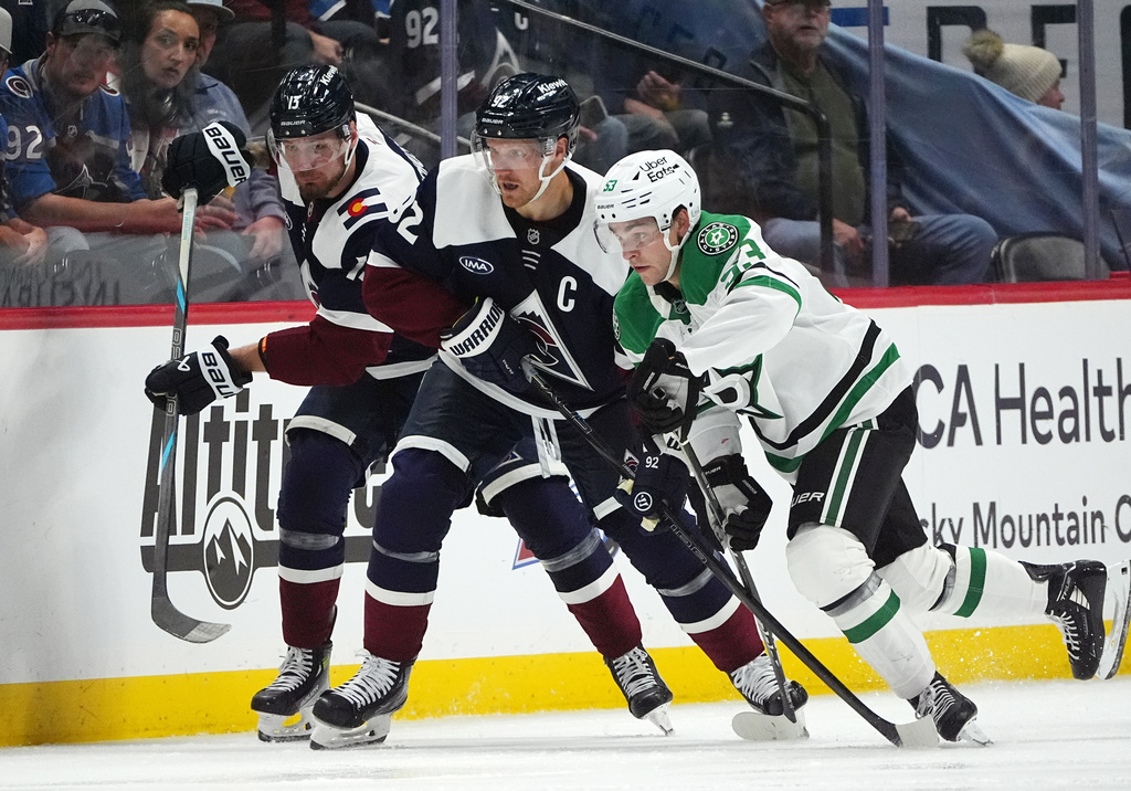 Dallas Stars center Wyatt Johnston, right, pursues the puck with Colorado Avalanche left wing Gabriel Landeskog, center, and right wing Valeri Nichushkin in the second period of an NHL hockey game against the Dallas Stars, Saturday, Oct. 11, 2025, in Denver. (AP Photo/David Zalubowski)
