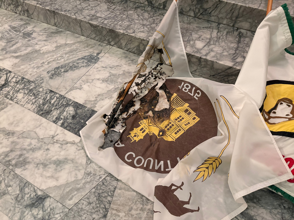 In this undated photo provided by the Department of Enterprise Services, a Washington state government agency, county flags sit burned on marble steps inside the capitol in Olympia, Wash., after an intruder broke in and vandalized the Legislative building on the evening of Oct. 5, 2025. (Department of Enterprise Services via AP)