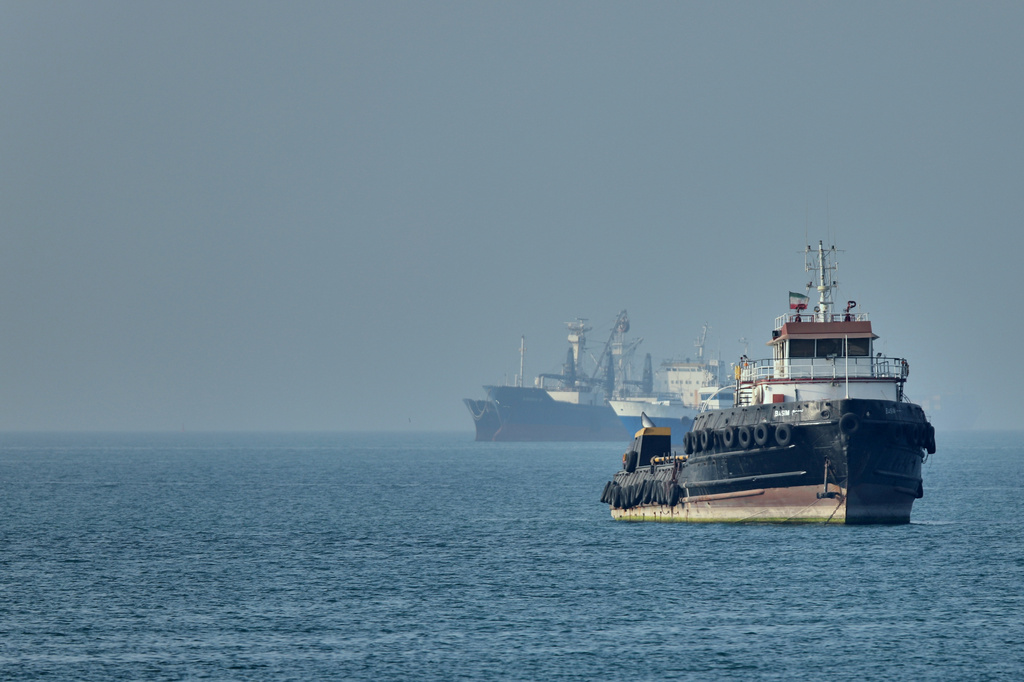 An Iranian tugboat floats in the foreground as cargo ships sit at anchor in the Strait of Hormuz off Bandar Abbas, Iran, Monday, May 4, 2026. (Amirhosein Khorgooi/ISNA via AP)