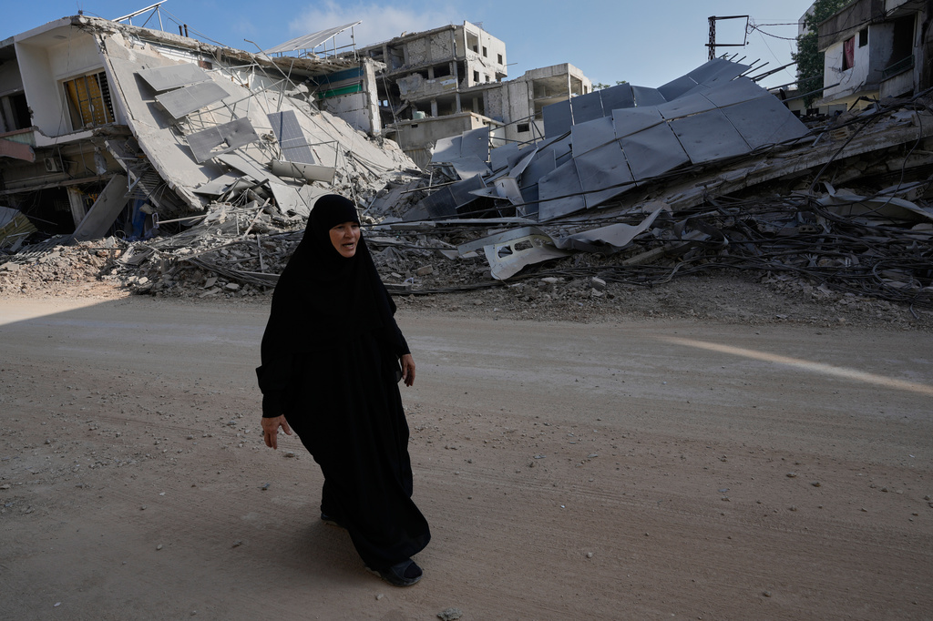 A woman returns to her village following the announcement of an initial ceasefire agreement between the United States and Iran, walks at her destroyed neighbourhood in Nabatiyeh town, southern Lebanon, Tuesday, June 16, 2026. (AP Photo/Hussein Malla)