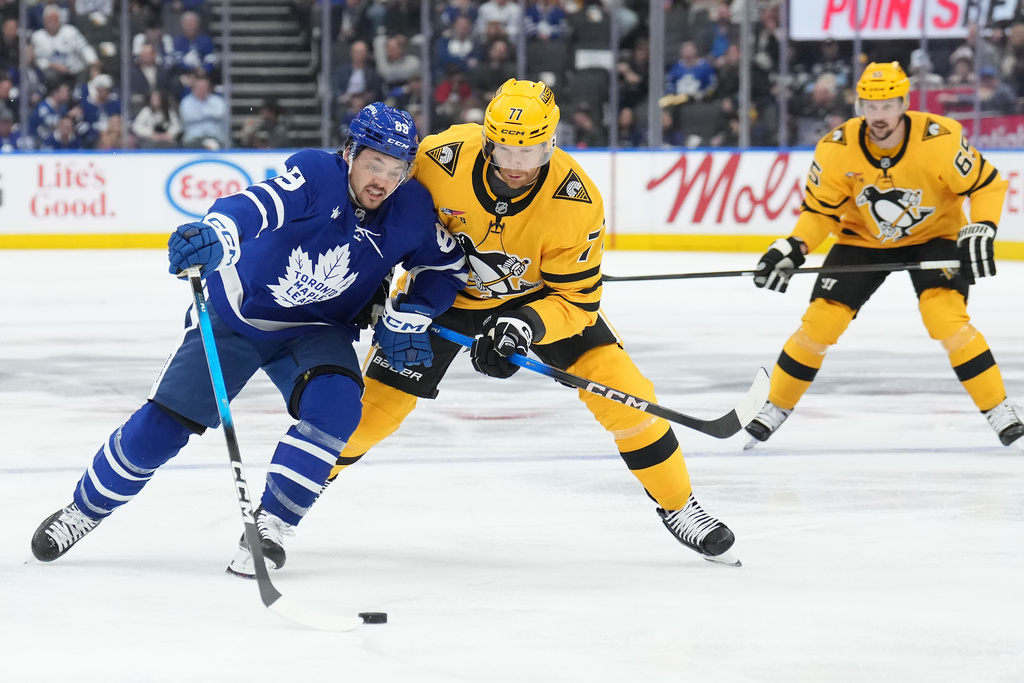 Toronto Maple Leafs forward Nicholas Robertson (89) battles for the puck with Pittsburgh Penguins defenceman Brett Kulak (77) during the second period of an NHL hockey game in Toronto, Tuesday, Dec. 23, 2025. (Nathan Denette/The Canadian Press via AP)