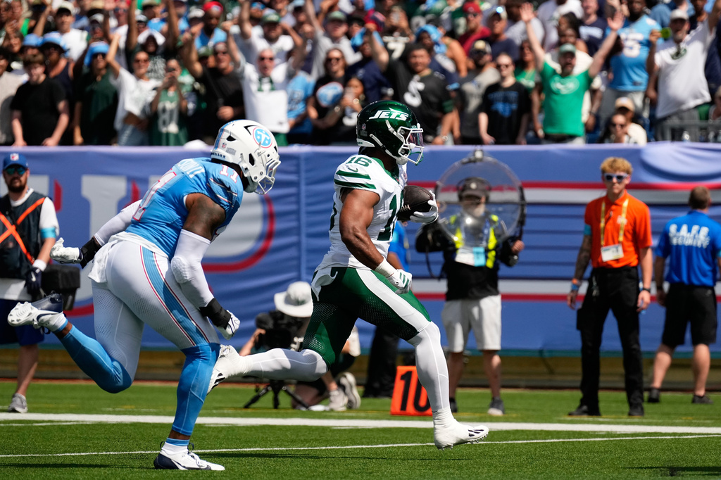 New York Jets tight end Kenyon Sadiq (16) runs in for a touchdown pursued by Tennessee Titans defensive end Jermaine Johnson II (11) during the first half of an NFL football game, Sunday, Sept. 13, 2026, in Nashville, Tenn. (AP Photo/George Walker IV)
