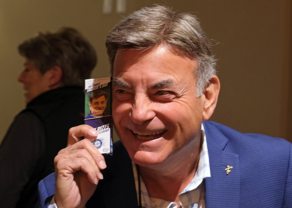 FILE - Rick Rizzs, Seattle Mariners radio broadcaster, poses with a talking bottle opener while handing them out before a baseball game against the Baltimore Orioles, June 23, 2019, in Seattle. (AP Photo/John Froschauer, File)