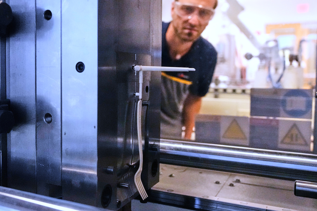 Peter Steeves, a polymer engineer at CJ Biomaterials, watches a compostable fork, made of plastic from plants, is molded in a testing laboratory Monday, Aug. 3, 2026, in Woburn, Mass. (AP Photo/Charles Krupa)