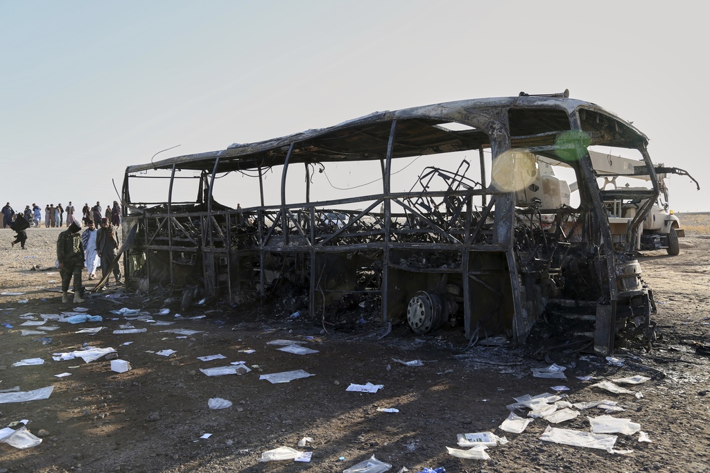 People and soldiers from the Taliban army inspect a burned-out bus that collided with a truck and a motorbike Tuesday evening, causing a massive fire and killing at least 70 people, including children, most of them Afghans returning from Iran, in western Herat province, Afghanistan, Wednesday, Aug. 20, 2025. (AP Photo/Omid Haqjoo)