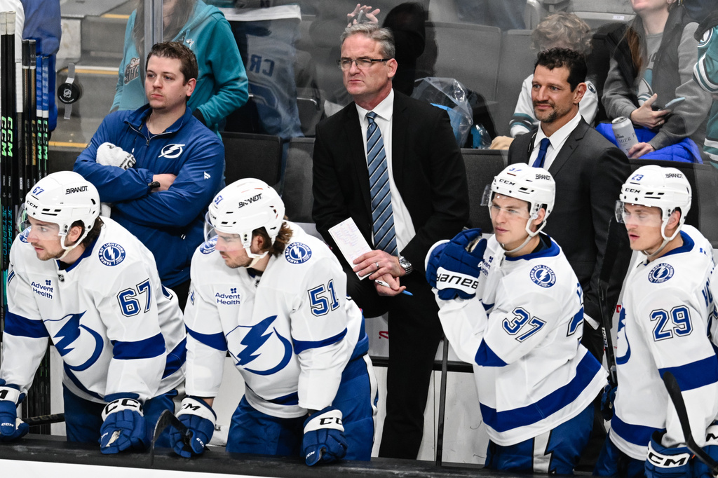 Tampa Bay Lightning head coach Jon Cooper, middle back, during the second period of an NHL hockey game Saturday, Jan. 3, 2026, in San Jose, Calif. (AP Photo/Thien-An Truong)