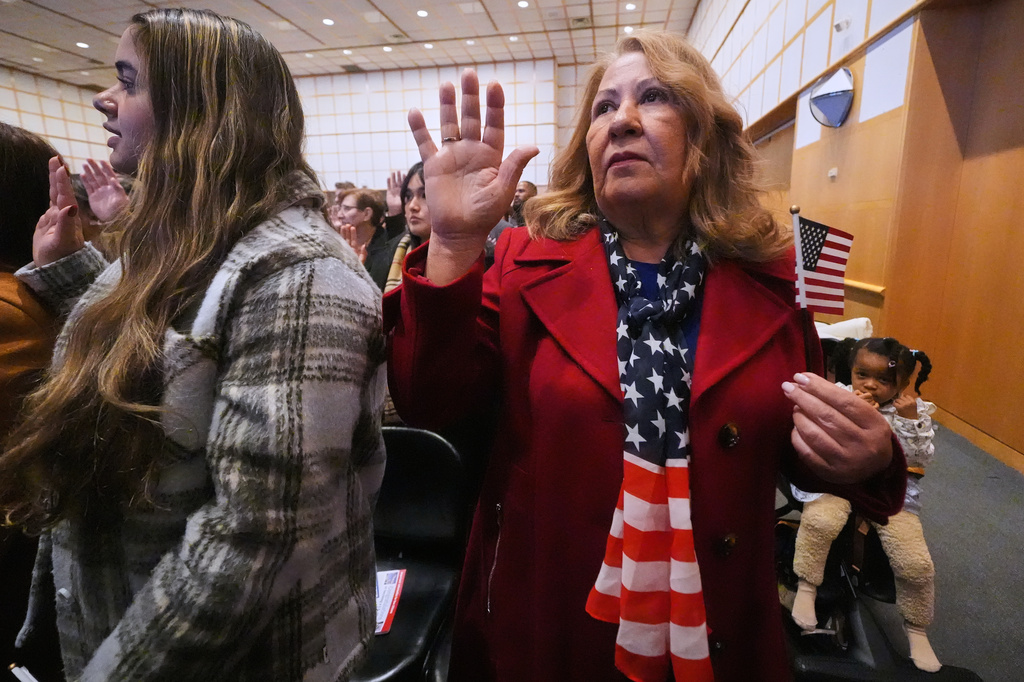 FILE - New citizen Ivette Lagos, originally from Brazil, wears a stars and stripes scarf while reciting the Oath of Allegiance during a naturalization ceremony where nearly 200 people from more than 50 different countries became United States citizens at the John F. Kennedy Presidential Library, Nov. 18, 2025, in Boston. (AP Photo/Charles Krupa, File)