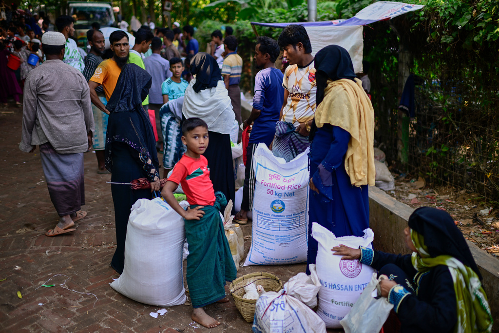 Rohingya refugees wait with their collected food rations before taking them home in the Rohingya refugee camp in Cox's Bazar, Bangladesh, Tuesday, Nov. 25, 2025. (AP Photo/Mahmud Hossain Opu)
