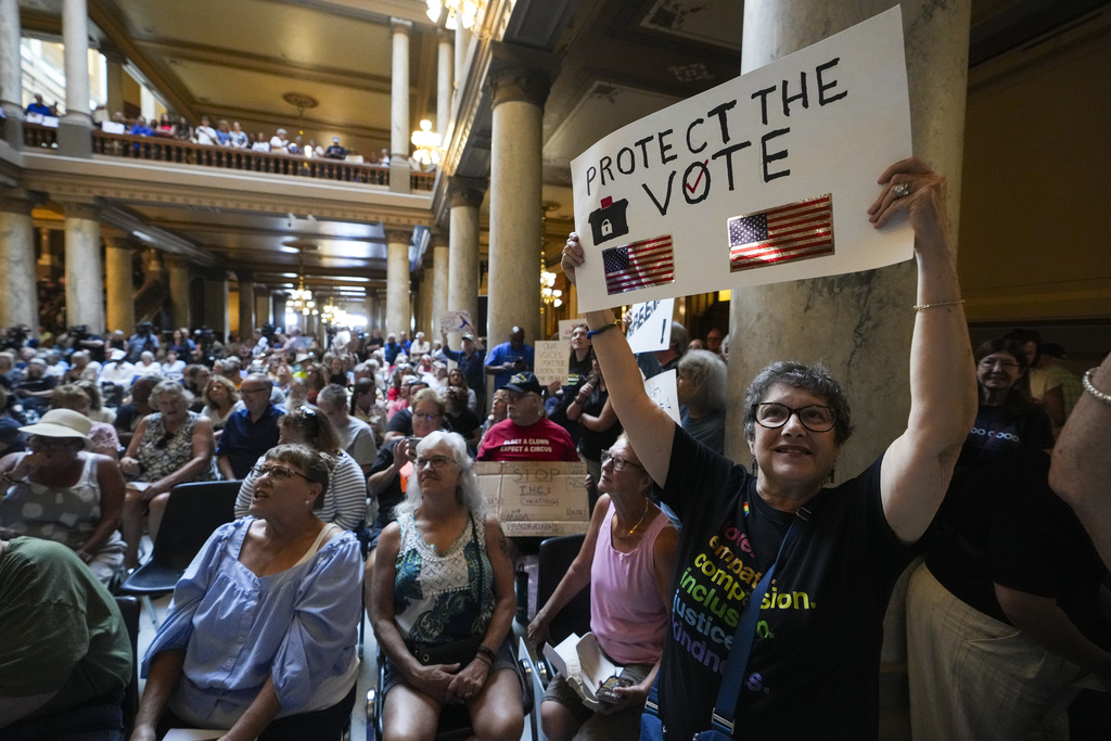 Annette Groos holds a sign before the start of a rally featuring former Transportation Secretary Pete Buttigieg at the Statehouse in Indianapolis, Thursday, Sept. 18, 2025 for Indiana Democrats amid pressure from President Donald Trump on Republicans who control the state's legislature to redistrict congressional seats. (AP Photo/Michael Conroy)