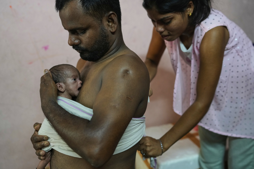 Antima Kumari helps her brother-in-law Sikandar Chaudhary hold his son close with the Kangaroo Mother Care (KMC), a skin-to-skin contact to promote bonding and well-being, at home in Gurugram, a satellite city of New Delhi, India, on Aug. 8, 2025. (AP Photo/Manish Swarup)