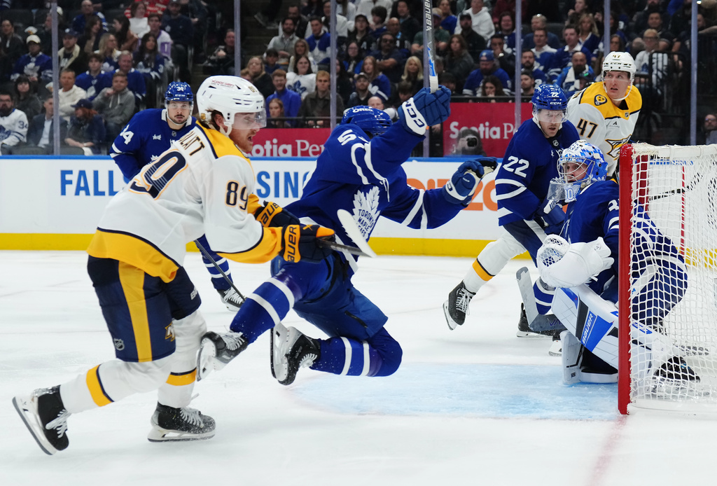 Nashville Predators' Ozzy Wiesblatt (89) checks Toronto Maple Leafs' Easton Cowan (53) as goaltender Cayden Primeau (30) looks on during third period NHL hockey action in Toronto on Tuesday, Oct. 14, 2025. (Nathan Denette/The Canadian Press via AP)