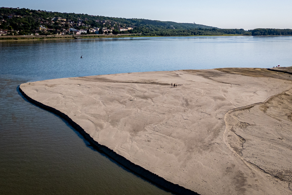 People walk on a bank of sand on the Danube River as usually submerged areas are exposed due to extreme low levels of the water following an extended period of drought in Oltenita, Romania, Saturday, Aug.1, 2026. (AP Photo/ Vadim Ghirda)