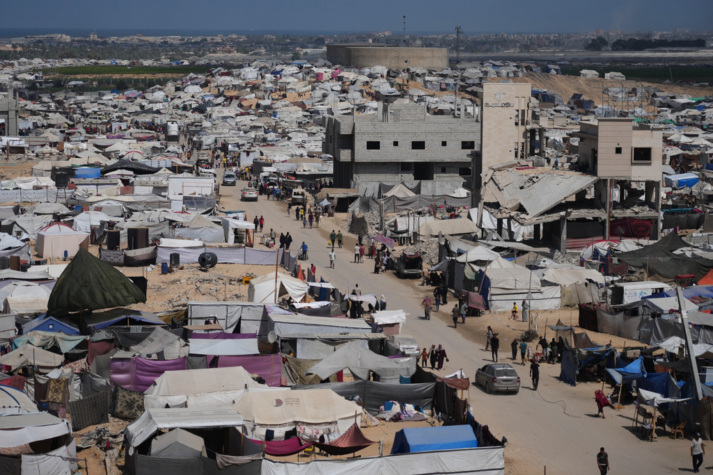 Displaced Palestinians walk through a tent camp in Muwasi, an area that Israel has designated as a safe zone, in Khan Younis southern Gaza Strip, Monday, Sept. 29, 2025. (AP Photo/Jehad Alshrafi)
