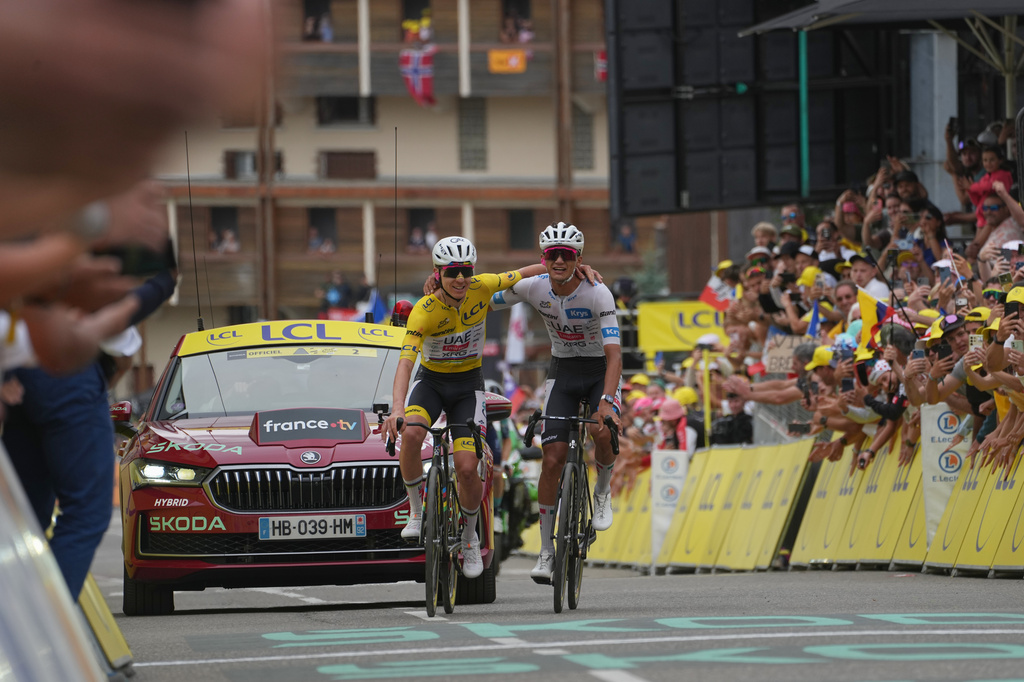 Slovenia's Tadej Pogacar, left, and Mexico's Isaac Del Toro, right, celebrate as they cross the finish line of the twentieth stage of the Tour de France cycling race with start in Le Bourg d'Oisans and finish in Alpe d'huez, France, Saturday, July 25, 2026. (AP Photo/Thibault Camus)