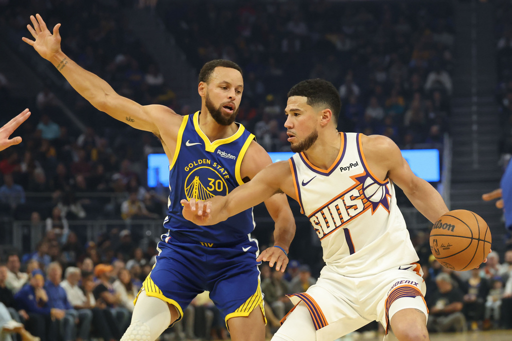 Phoenix Suns guard Devin Booker (1) drives to the basket against Golden State Warriors guard Stephen Curry (30) during the first half of an NBA basketball game in San Francisco, Tuesday, Nov. 4, 2025. (AP Photo/Jed Jacobsohn)