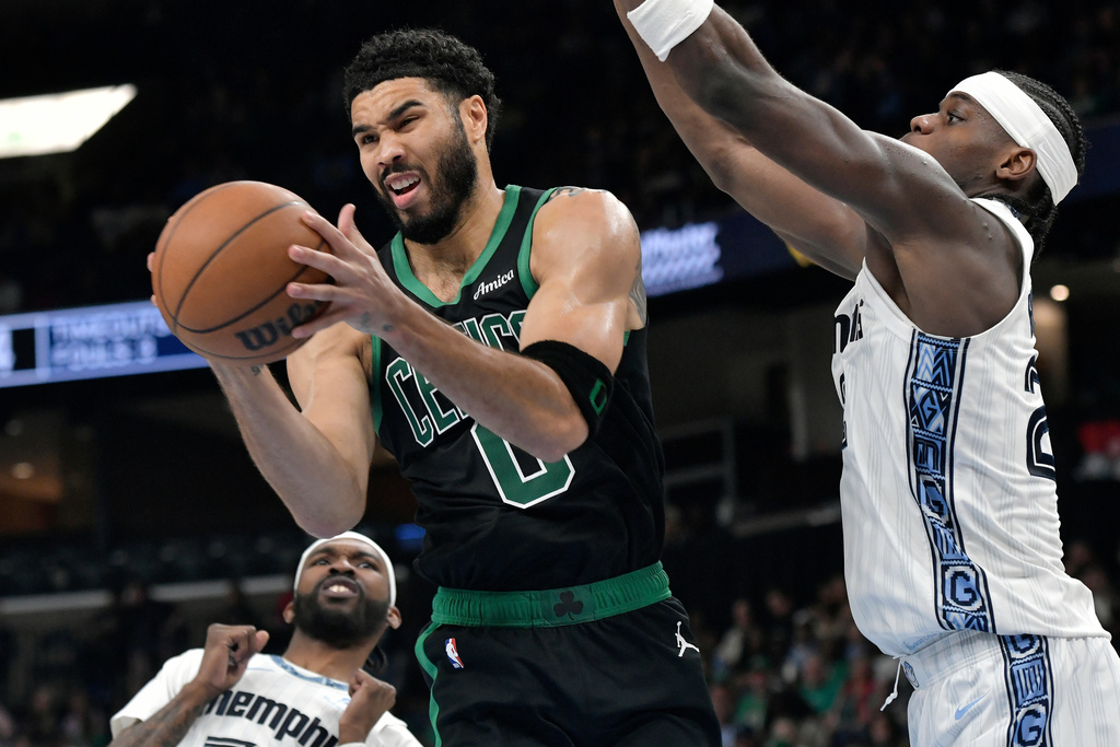 Boston Celtics forward Jayson Tatum (0) handles the ball between Memphis Grizzlies forward Taylor Hendricks, right, and guard DeJon Jarreau, left, in the second half of an NBA basketball game Friday, March 20, 2026, in Memphis, Tenn. (AP Photo/Brandon Dill)