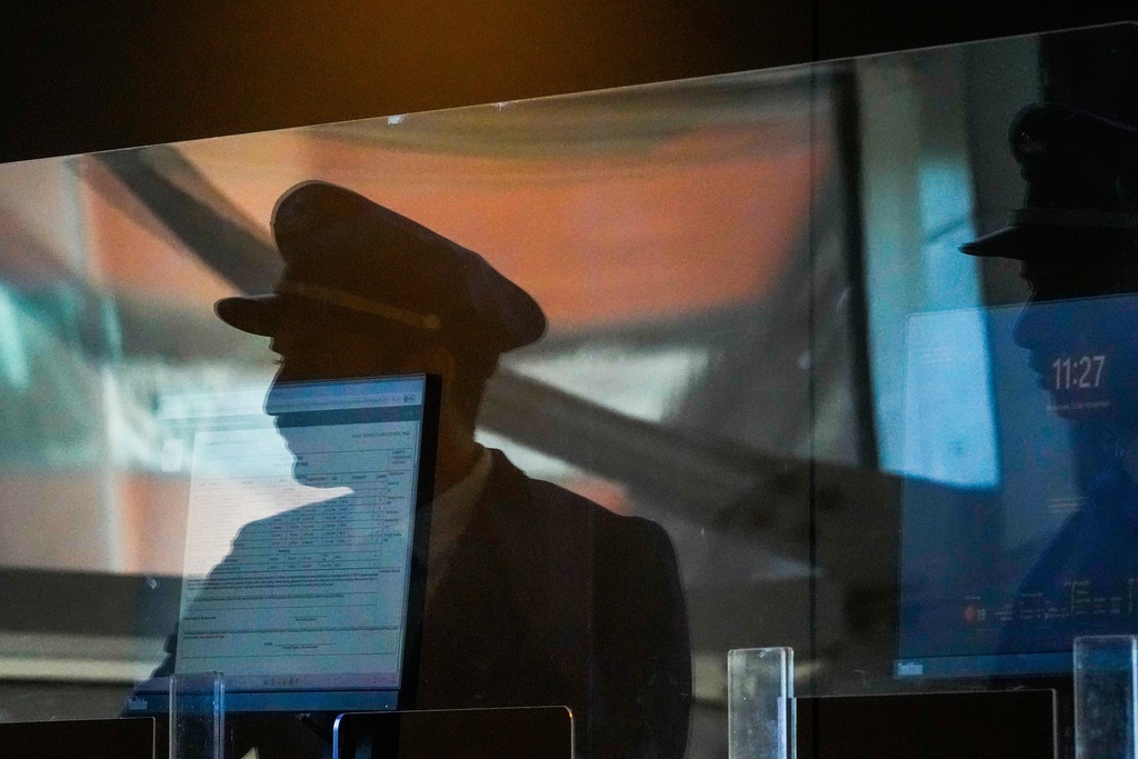 Airplane pilots reflected in a window at the check-in area for Latam airlines arrive for work at Arturo Merino Benitez airport in Santiago, Chile, Wednesday, Nov. 12, 2025, during a strike by pilots who belong to the pilots' union that is demanding higher salaries. (AP Photo/Esteban Felix)