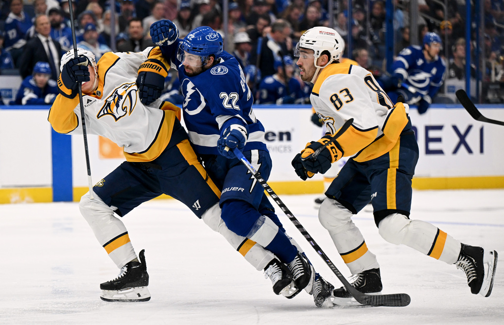 Tampa Bay Lightning right wing Oliver Bjorkstrand (22) races for the puck against Nashville Predators right wing Matthew Wood (71) and defenseman Adam Wilsby (83) during the second period of an NHL hockey game, Sunday, March 29, 2026, in Tampa, Fla. (AP Photo/Jason Behnken)