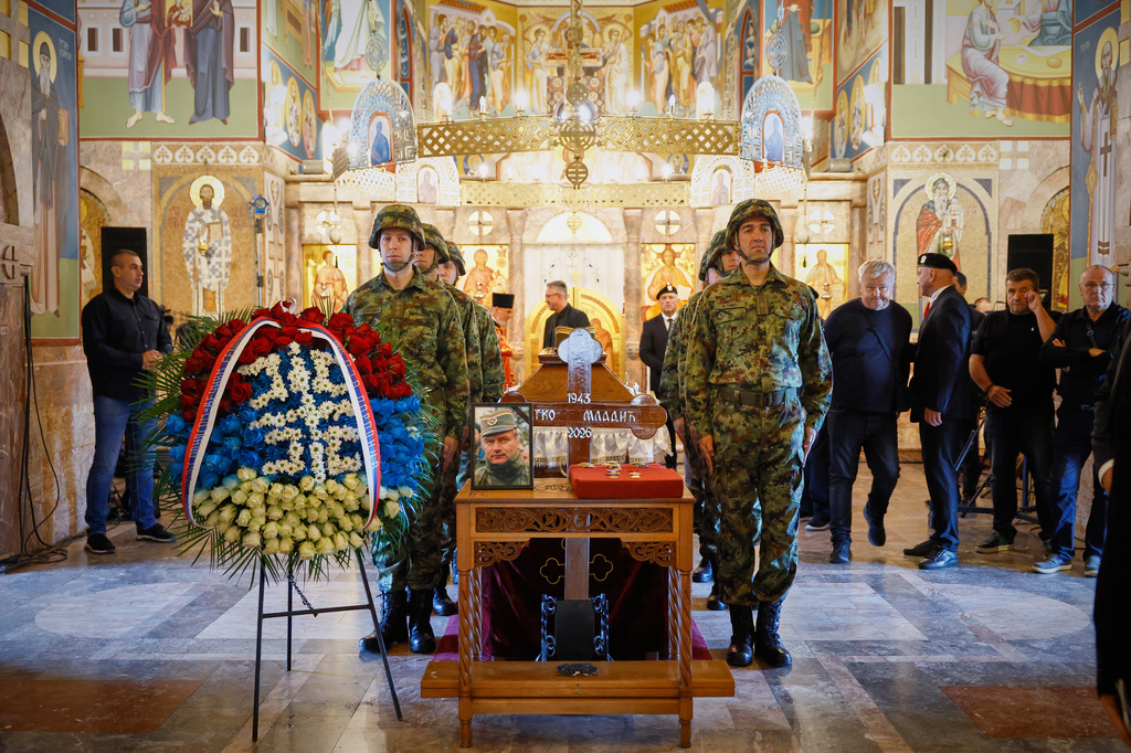 A man touches the cross as Serbian national military servicemen stand around the coffin of the former Bosnian Serb army commander Ratko Mladic, who died last week while serving a life sentence for genocide and other atrocities during the war in Bosnia, at the St. Luka Church, in Belgrade, Serbia, Monday, Sept. 7, 2026. (AP Photo/Marko Drobnjakovic)
