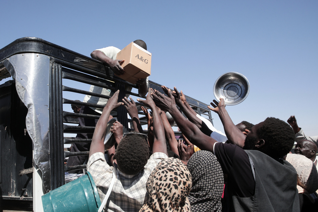 Sudanese families displaced from El-Fasher reach out as aid workers distribute food supplies at the newly established El-Afadh camp in Al Dabbah, in Sudan's Northern State, Sunday, Nov. 16, 2025. (AP Photo/Marwan Ali)