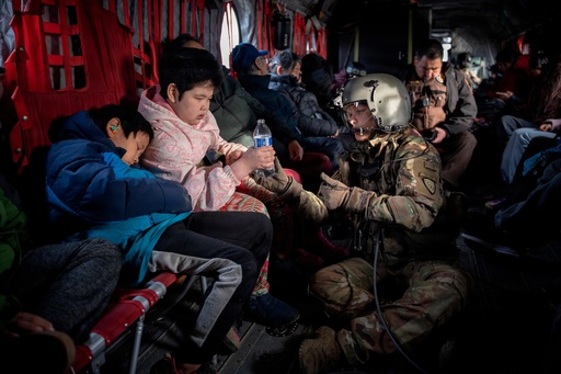 In this photo provided by the Alaska Army National, Guard Sgt. Mary Miller, a helicopter crew chief, passes a bottle of water to a child while evacuating displaced people from Kwigillingok, Alaska, during recovery operations on Thursday, Oct. 16, 2025. (Joseph Moon/Alaska National Guard via AP) In this photo provided by the Alaska Army National, Guard Sgt. Mary Miller, a helicopter crew chief, passes a bottle of water to a child while evacuating displaced people from Kwigillingok, Alaska, during recovery operations on Thursday, Oct. 16, 2025. (Joseph Moon/Alaska National Guard via AP)