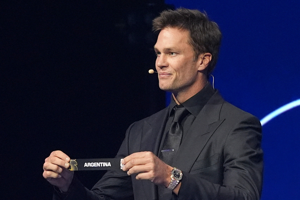 Former NFL player Tom Brady holds up the team name of Argentina during the draw for the 2026 soccer World Cup at the Kennedy Center in Washington, Friday, Dec. 5, 2025. (AP Photo/Jacquelyn Martin)