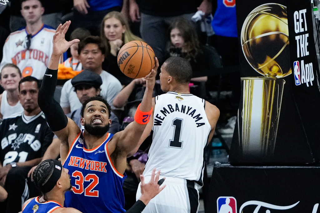 New York Knicks center Karl-Anthony Towns (32) rebounds over San Antonio Spurs forward Victor Wembanyama during the second half of Game 5 of the NBA Finals basketball series, Saturday, June 13, 2026, in San Antonio. (AP Photo/Ross D. Franklin)