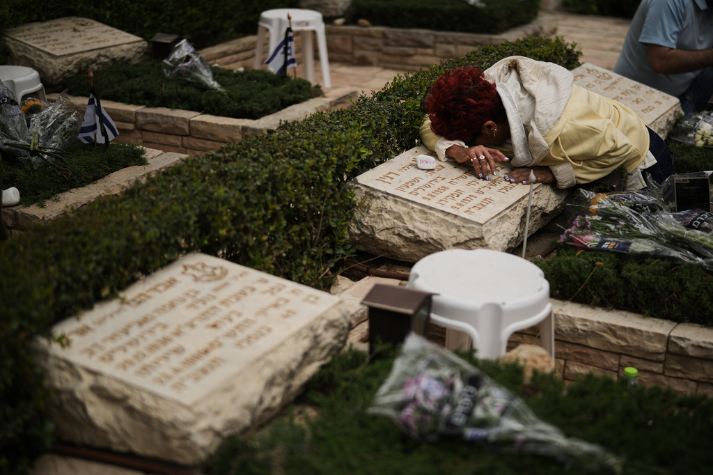 A woman weeps over the grave of her relative as Israel marks the annual Memorial Day, honoring soldiers killed in the nation's conflicts and victims of nationalistic attacks, at Mount Herzl military cemetery in Jerusalem, Tuesday, April 21, 2026. (AP Photo/Leo Correa)