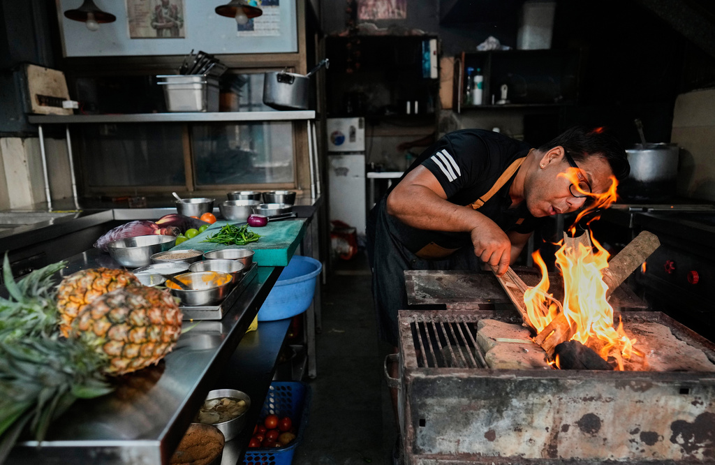 Atul Lahkar, from the Assam region, chef lights a fire with wood and coal to prepare food for his restaurant following a regional gas shortage in Guwahati, India, Thursday, March 19, 2026. (AP Photo/Anupam Nath)
