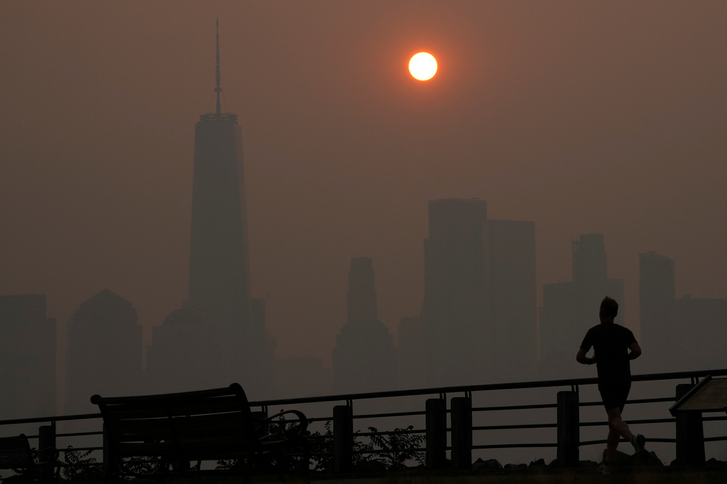 FILE - A man runs in front of the sun rising over the lower Manhattan skyline in Jersey City, N.J., June 8, 2023. (AP Photo/Seth Wenig, File)