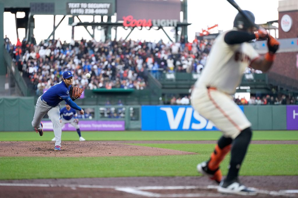 Los Angeles Dodgers pitcher Shohei Ohtani, left, throws to a San Francisco Giants' Heliot Ramos, right, during the second inning of a baseball game Wednesday, April 22, 2026, in San Francisco. (AP Photo/Tony Avelar)