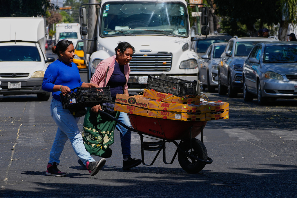 Fruit vendors walk along a street in Guadalajara, Mexico, on Tuesday, Feb. 24, 2026. (AP Photo/Marco Ugarte)