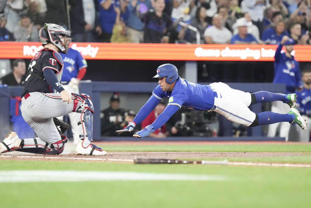Toronto Blue Jays' George Springer (right) scores a run as Minnesota Twins catcher Ryan Jeffers (27) looks on during third inning MLB baseball action in Toronto on Wednesday, August 27, 2025. (Chris Young/The Canadian Press via AP)