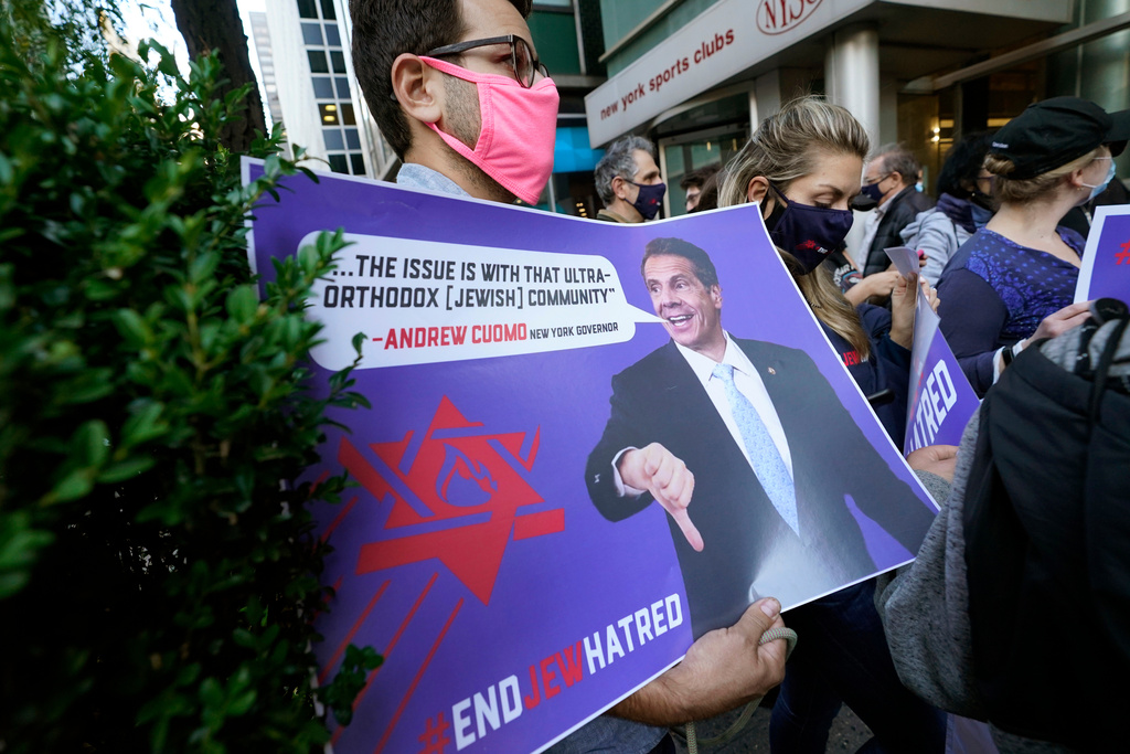 FILE - A man holds a sign as he joins protesters outside the offices of New York Gov. Andrew Cuomo, Oct. 15, 2020, in New York. (AP Photo/Kathy Willens, File)