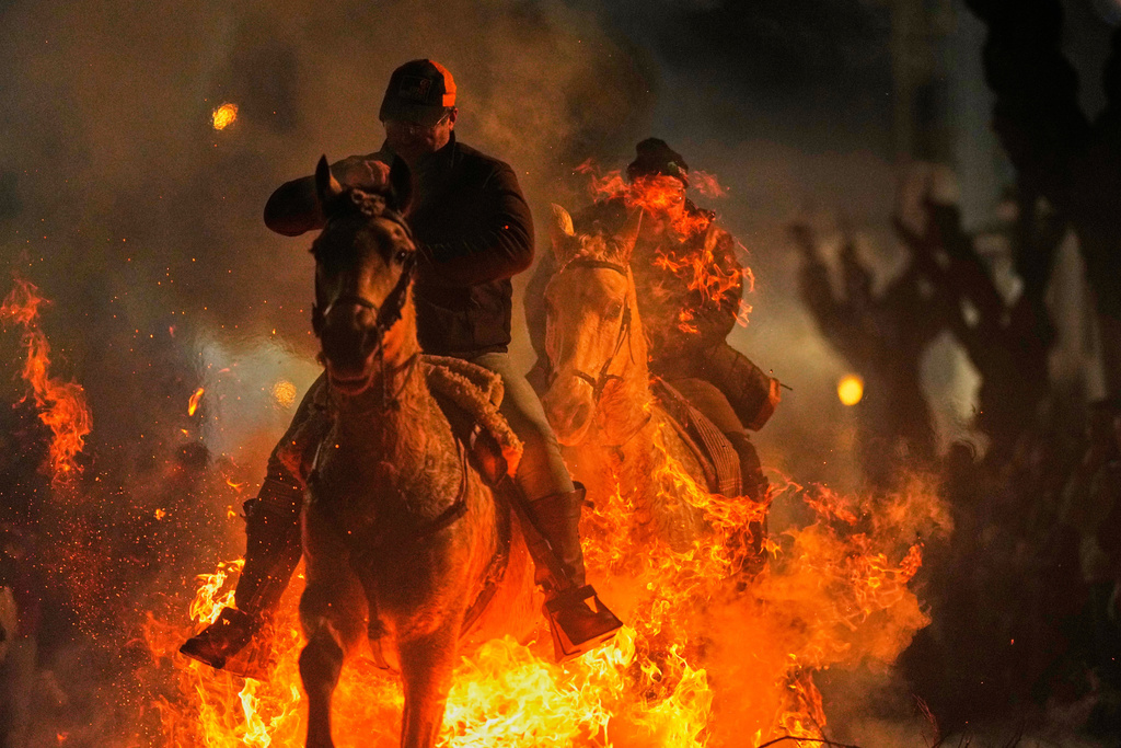 Men ride horses through a bonfire as part of a ritual in honor of Saint Anthony the Abbot, the patron saint of domestic animals, in San Bartolome de Pinares, Spain, Friday, Jan. 16, 2026. (AP Photo/Manu Fernandez)