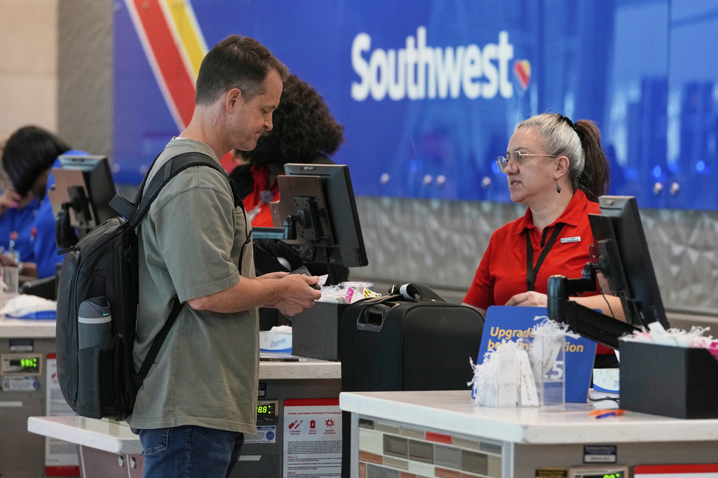 Southwest airlines ticketing agent, Nury Perez, right, assists a traveler at Dallas Love Field Airport, Friday, Aug. 29, 2025, in Dallas. (AP Photo/Tony Gutierrez)