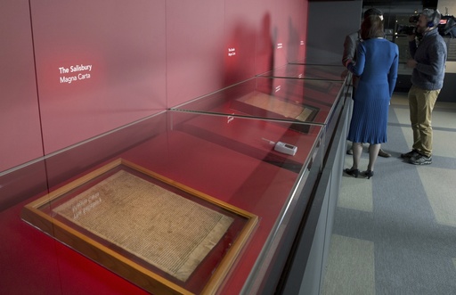 FILE - members of the media film four of the original surviving Magna Carta manuscripts that have been brought together by the British Library for the first time, during a media preview in London, Monday, Feb. 2, 2015. Two environmental activists have attacked a glass case containing an original copy of the Magna Carta at the British Library, causing minor damage to the re-enforced box but leaving the historic document unscathed on Friday, May 10, 2024. (AP Photo/Alastair Grant, File)