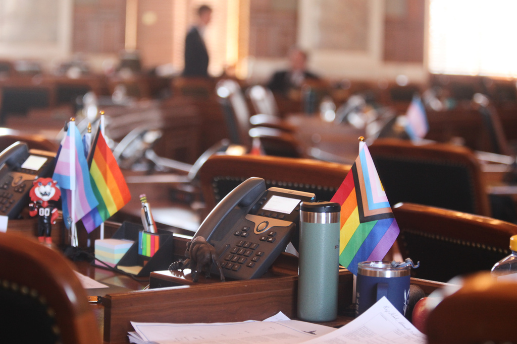 Small transgender and LGBTQ rights flags sit on the desks of Kansas state Reps. Tobias Schlingensiepen, right, D-Topeka, and Kirk Haskins, left, also D-Topeka, in the Kansas House chamber, protesting a new law that will prevent transgender people from changing their driver's licenses and birth certificates to reflect their gender identities and nullify past changes, Thursday, Feb. 19, 2026, at the Statehouse in Topeka, Kansas. (AP Photo/John Hanna)