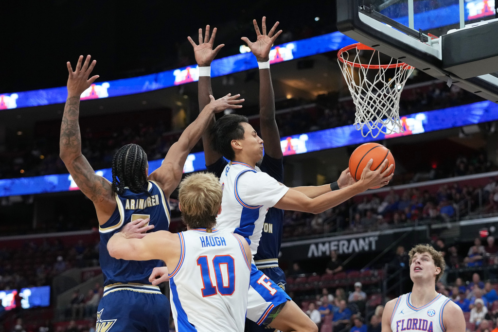 Florida guard Xaivian Lee, center, goes to the basket during the first half of an NCAA college basketball game against George Washington at the Orange Bowl Basketball Classic, Saturday, Dec. 13, 2025, in Sunrise, Fla. (AP Photo/Lynne Sladky)