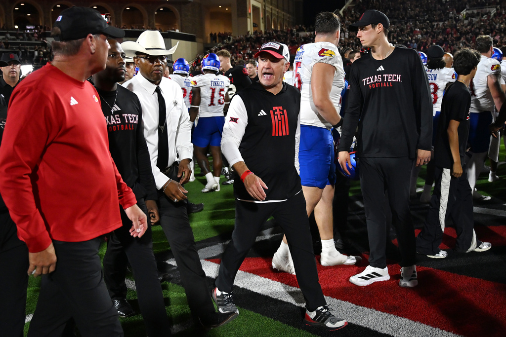 Texas Tech head coach Joey McGuire, center, speaks to Kansas head coach Lance Leipold, left, after the end of the NCAA college football game, Saturday, Oct. 11, 2025, in Lubbock, Texas. (AP Photo/Annie Rice)