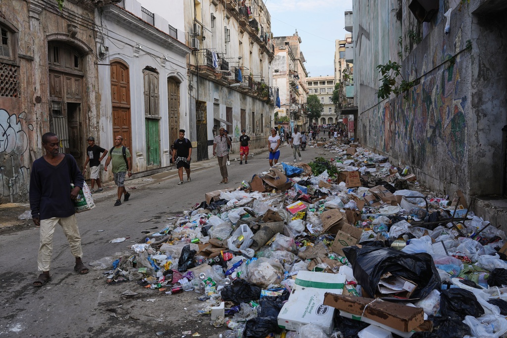 People walk next to trash on a street in Havana, Monday, Jan. 26, 2026. (AP Photo/Ramon Espinosa)